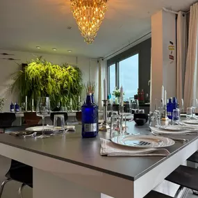 Geschlossene Gesellschaft präsentiert einen edel gedeckten Esstisch mit stilvoller Tischdekoration, Gläsern und modernem Ambiente unter einem goldenen Kronleuchter in Hamburg.
