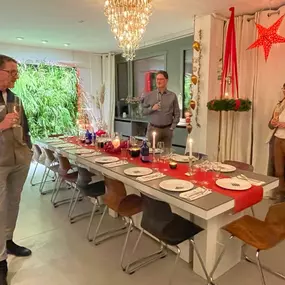 Geschlossene Gesellschaft zeigt eine festlich gedeckte Tafel mit Kerzen, roter Tischdekoration und Gästen bei einem exklusiven Abendessen in Hamburg.
