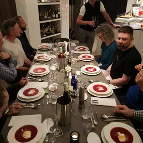 Geschlossene Gesellschaft lädt zu einem stilvollen Dinnerabend ein: Gäste genießen Rote-Bete-Suppe bei Kerzenschein in exklusiver Atmosphäre in Hamburg.