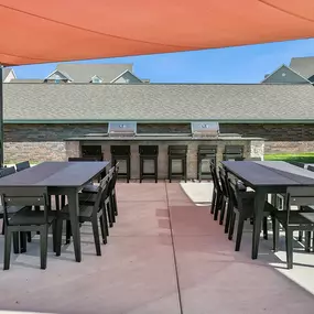 a patio with tables and chairs under an orange tent