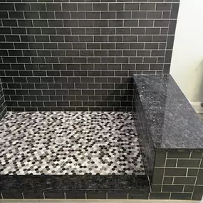 A custom mosaic tiled floor is shown in a luxurious entryway. The design features a large circular pattern of white and blue tiles, framed by a dark border and set within a field of polished white marble.