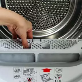 A close up of a person removing the lint filter from a clothes dryer, emphasizing the importance of routine dryer maintenance