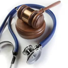 A wooden gavel and a blue stethoscope are arranged on a white background, symbolizing the legal and medical aspects of a case.