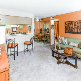 View of the living room with a green couch, orange accent wall, and breakfast bar