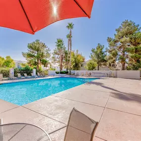Resort-style pool with a table and chairs with an orange umbrella in front of it