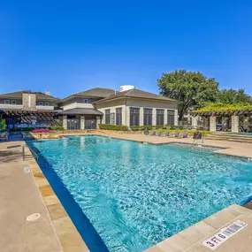 Beautiful swimming pool with tree lined view and lounge chairs