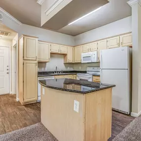 Interior kitchen with wooden cabinetry, modern appliances, and granite counter top