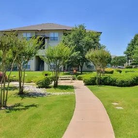 Walk way leading up to the leasing office surrounded by green lawn and trees