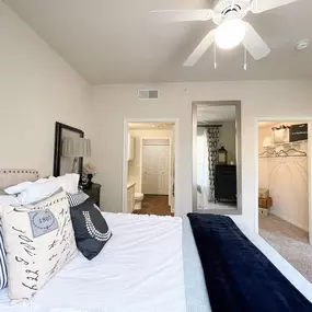Interior bedroom with mirror, walk-in style closet, and white walls