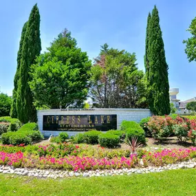 Front entrance to apartment building with green lawn, flowers, and property sign