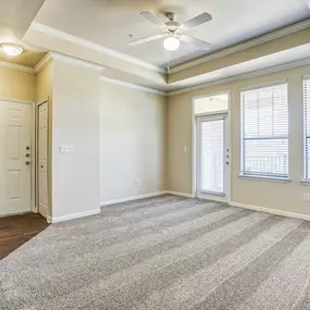 Interior apartment living room with ample natural light, beige carpeting, and light yellow walls