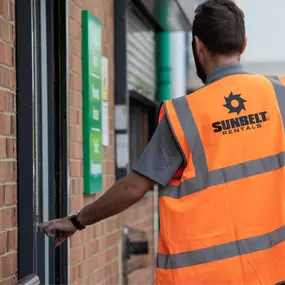 Sunbelt Rentals team member wearing a branded high-visibility vest entering a depot building.