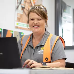 Sunbelt Rentals team member working at a depot desk with a laptop and wearing branded uniform.