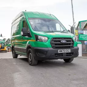Sunbelt Rentals branded green Ford Transit van leaving a depot yard.