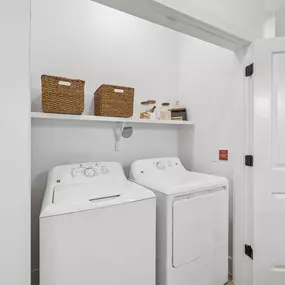 In-unit laundry area with a washer, dryer, and storage shelf.