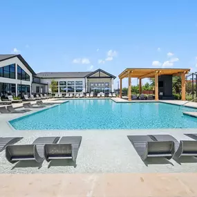 Outdoor swimming pool with lounge chairs and a covered seating area at an apartment community.