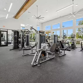 Fitness center with weight machines, cardio equipment, and large windows.