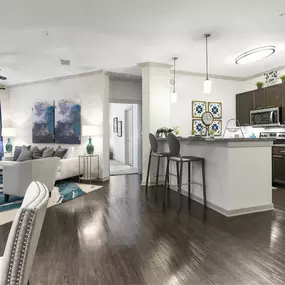 a living room and kitchen area with white walls and wood flooring