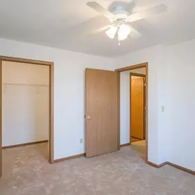 A room with a ceiling fan and three doors.