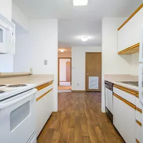 A kitchen with white appliances and wooden floors.
