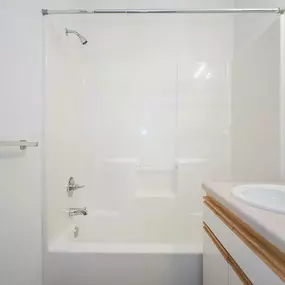 A white bathroom with a tub, sink and mirror.