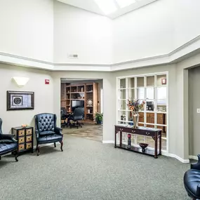 A living room with a grey carpet and black leather chairs.