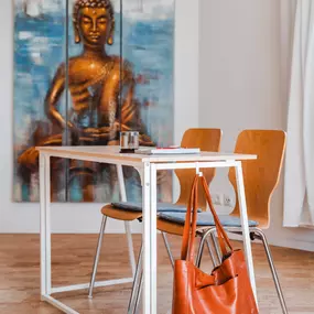 Webstudio Dresden Stilvoll eingerichteter Raum mit Buddha-Kunstwerk, Tisch und Stühlen, inspirierende Atmosphäre für Gespräche.