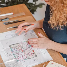 Webstudio Dresden Kreativer Arbeitsprozess am Tisch, Frau zeichnet Grundriss mit Markern, Symbol für Planung und visuelle Konzepte.