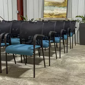 Multiple commercial chairs set up in a line with warm artwork in the background and plants