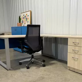 Workstations set up with black task chair light wood table top and pedestal drawers with feminine artwork