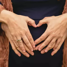 Kara Elizabeth Photography Detailaufnahme von Händen in Herzform über dem Bauch – Schwangerschaftsfotografie in München, die Vorfreude auf das Baby liebevoll dokumentiert.