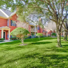 Exterior of apartment with grassy lawn and trees