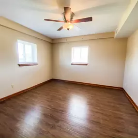 An empty bedroom with wooden floors and a ceiling fan
