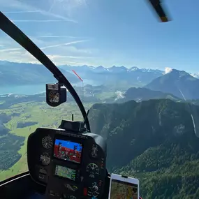 A spectacular view captured during a FunFlights scenic helicopter tour! From inside the cockpit, with the rotor blade in sight, guests can admire the impressive Stockhorn mountain rising above lush green forests, the turquoise-blue Lake Thun shimmering be