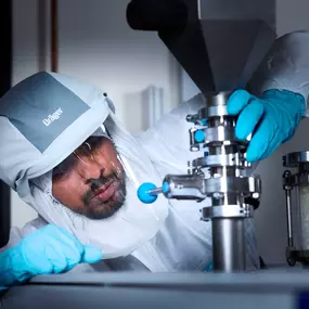 Foto und Filmproduktion Laila Tkotz Forscher im Reinraum prüft industrielle Laboranlage mit Schutzanzug und Handschuhen