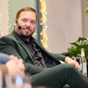Foto und Filmproduktion Laila Tkotz Mann im Business-Outfit spricht bei Interviewveranstaltung mit Mikrofon