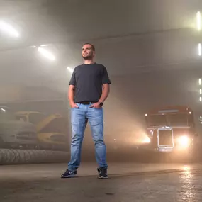 Foto und Filmproduktion Laila Tkotz Porträtaufnahme in Industriehalle mit klassischen Fahrzeugen und Scheinwerfern