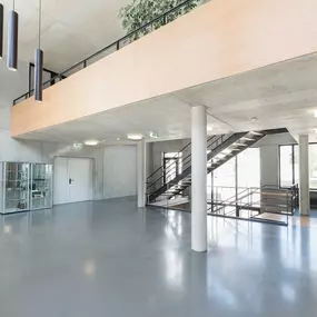 Foto und Filmproduktion Laila Tkotz Weitwinkelaufnahme von lichtdurchflutetem Eingangsbereich mit Glas und Beton