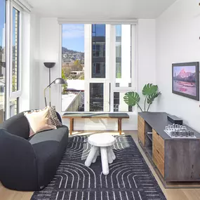 a living room with a black couch and a black and white rug and a window