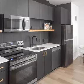 a kitchen with black cabinets and stainless steel appliances and a sink