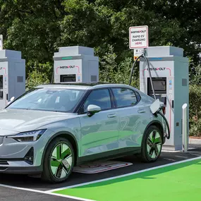 An electric vehicle charges at an InstaVolt bay at Country House Estates, Exeter, with clearly marked EV-only and accessible green bays.