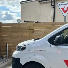 An InstaVolt-branded electric van is parked beside a charging unit at a dedicated EV bay, with clear signage and branding enhancing visibility of the site.