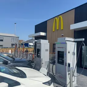 Several EVs charging at InstaVolt units outside a McDonald’s, with nearby industrial buildings in the background.