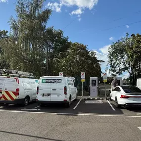 Wide shot of the InstaVolt charging area at Mile House, with vans and cars actively charging under clear signage.