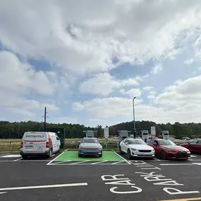 Four electric vehicles, including a BMW and a Polestar, charging at InstaVolt units on the A64 with green-painted charging bays and clear parking signage.