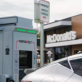Detail view of an InstaVolt ultra-rapid charger beside a silver EV, with McDonald’s Crawley clearly visible in the background.