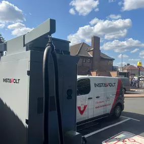 Rear view of an InstaVolt charger with a branded van and McDonald’s in the background, showcasing the convenient EV charging point in Enfield.