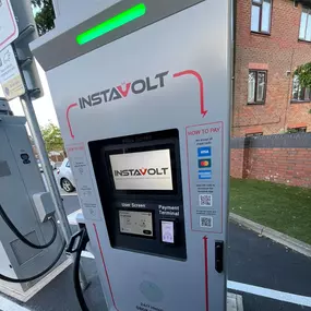 Close-up of an InstaVolt ultra-rapid charger with touch-screen, card payment terminal, and clear instructions, located in a dedicated EV bay for quick, convenient top-ups