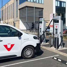 White electric van plugged into InstaVolt ultra rapid chargers in a sunny car park.