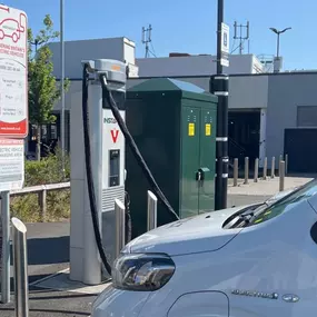 White InstaVolt electric van charging at twin ultra rapid chargers outside a modern building.
